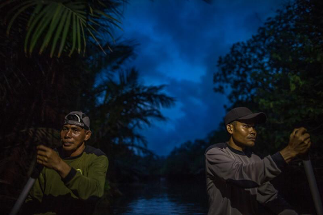 Rangers paddling down a river at night in search of Javan Rhino in Ujung Kulon National Park, Java. Photo by Robin Moore, Re:wild.